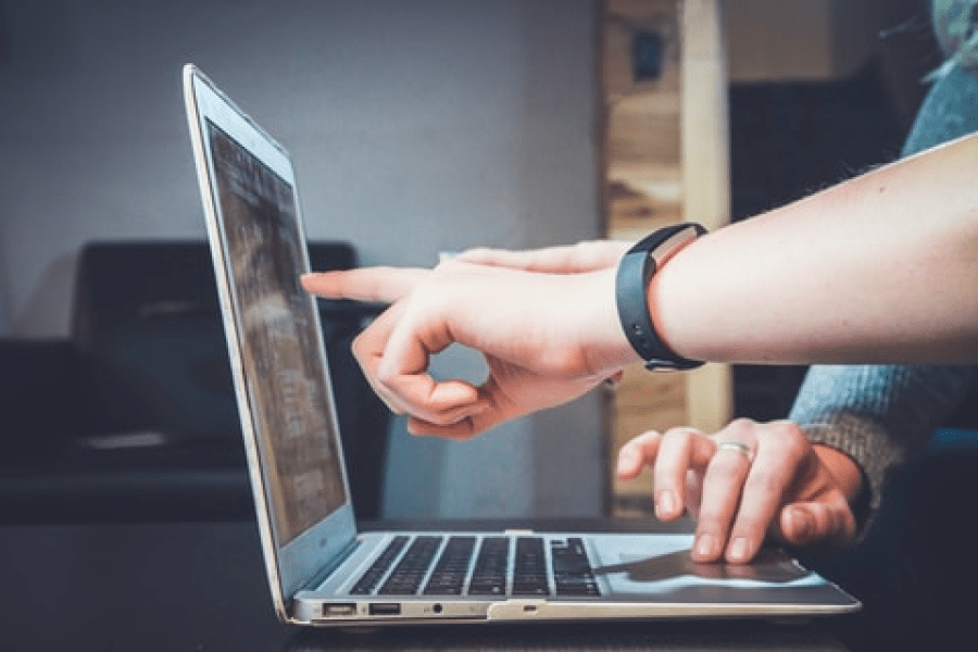 En hand pekar på datorskärm för att visa personen bredvid något