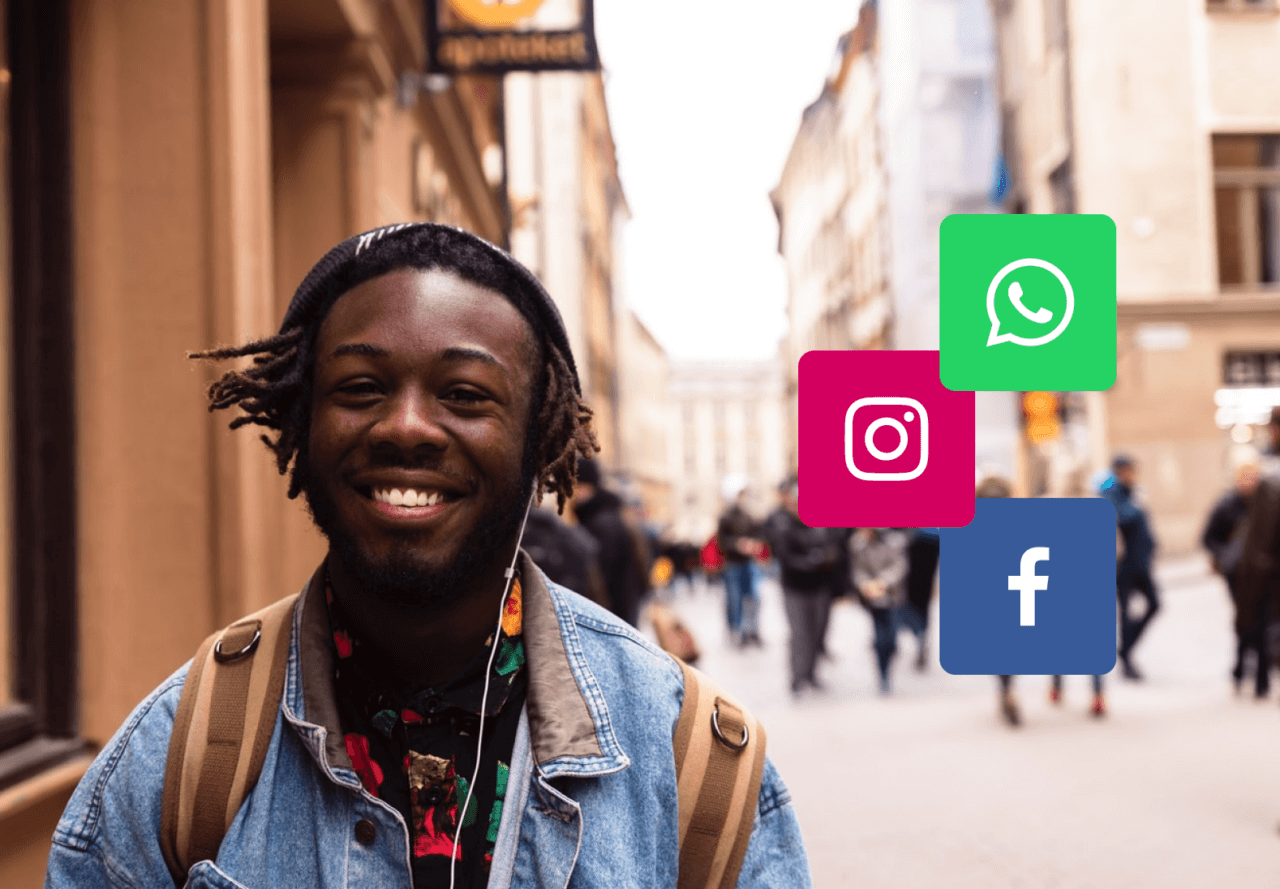 Porträtt av leende ung man på gatan med instagram, whatsapp och facebook logotyper