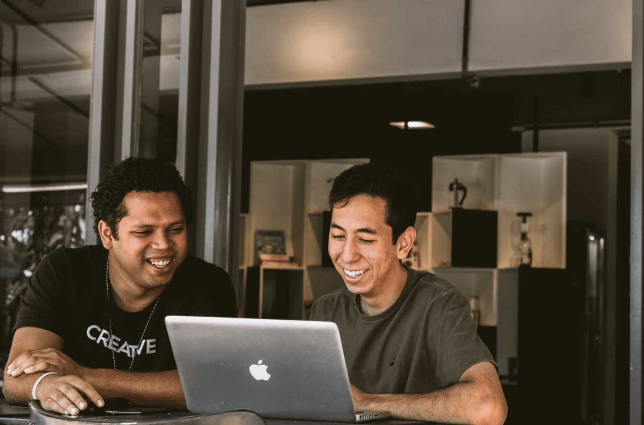 Två killar sitter vid en laptop och skrattar