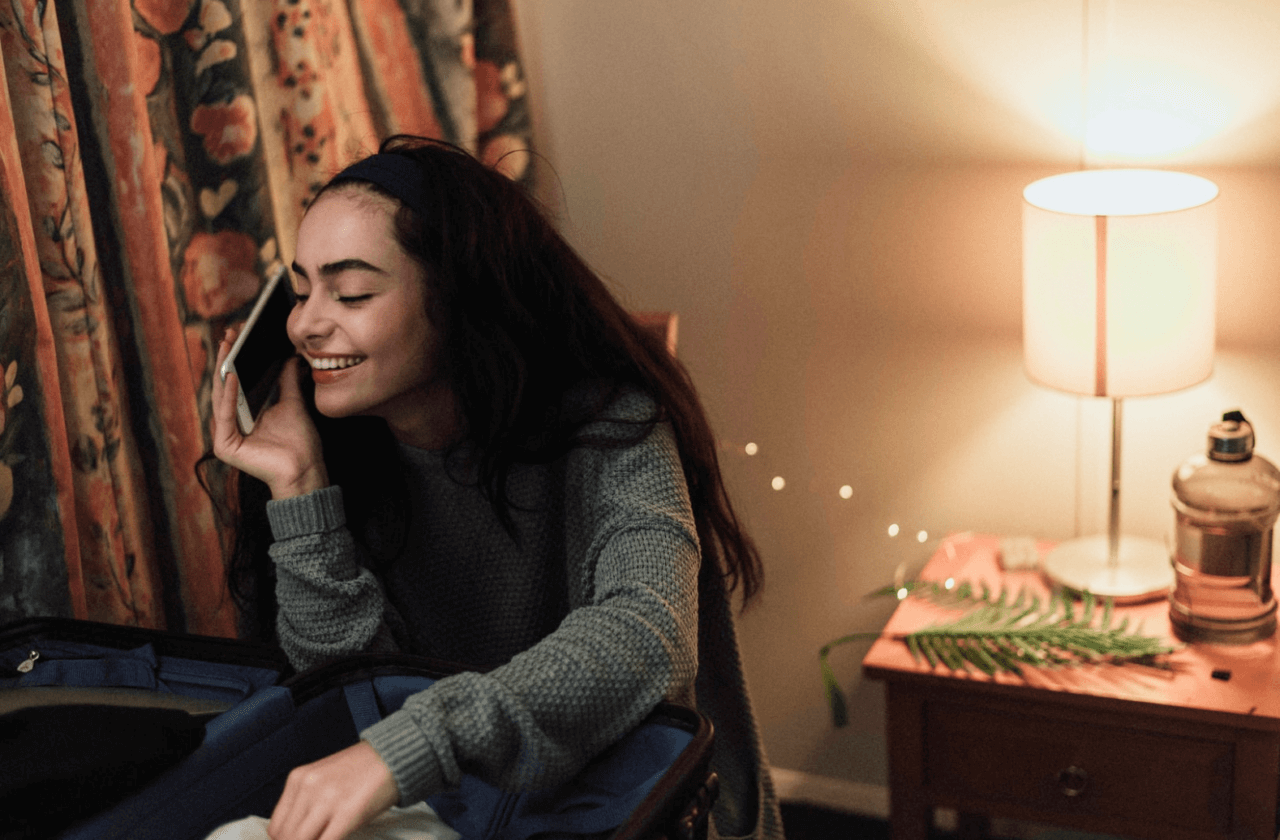En leende kvinna pratar i telefon i lägenhet
